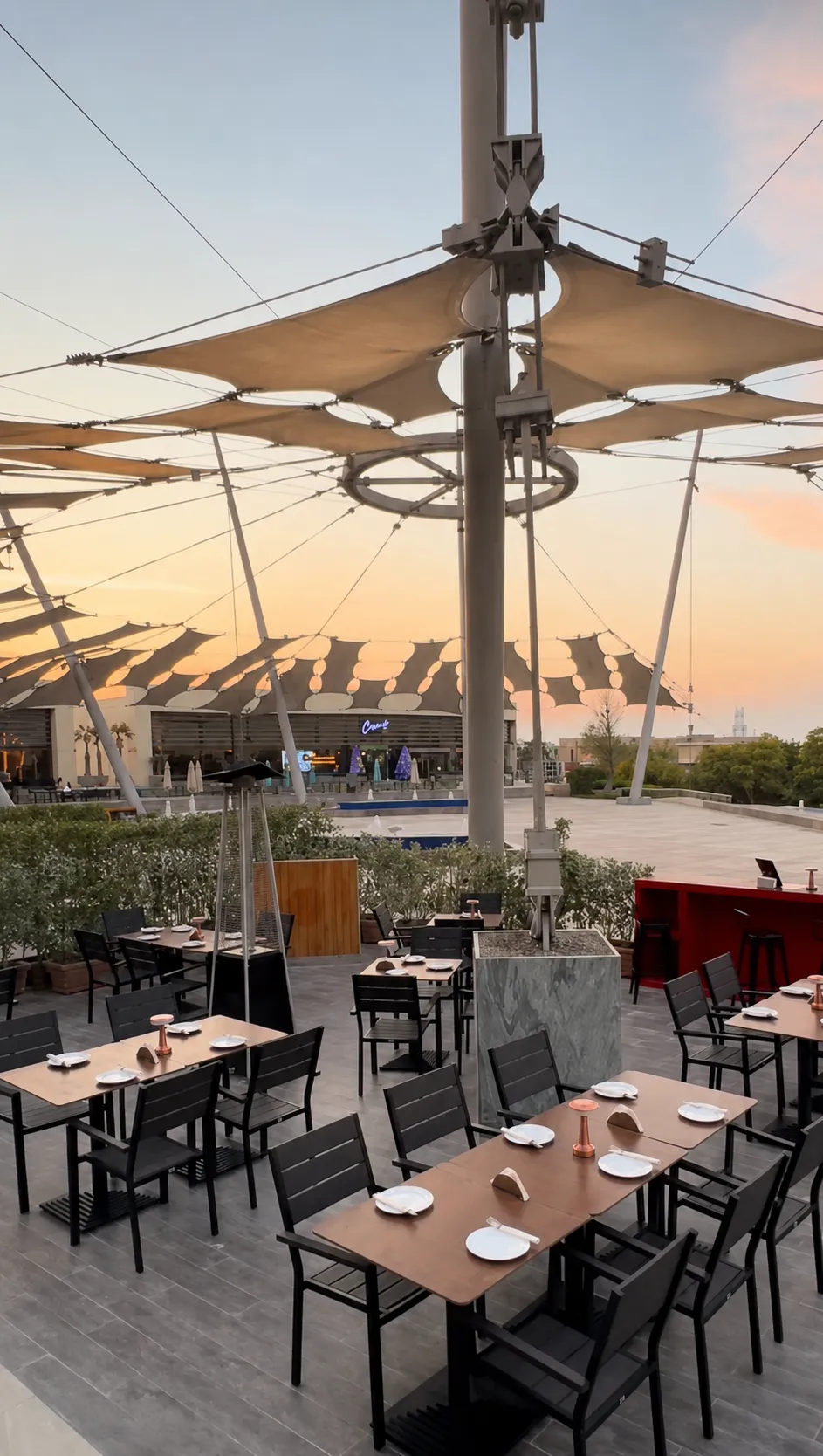 Outdoor restaurant seating area with a large canopy at sunset